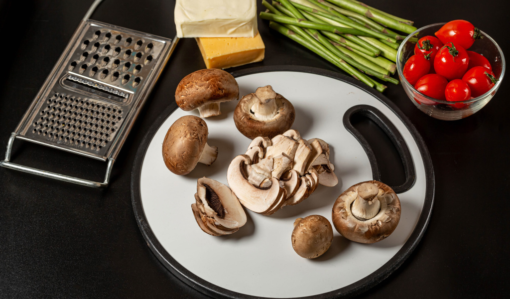 Шампиньоны на столе со спаржей и помидорами 