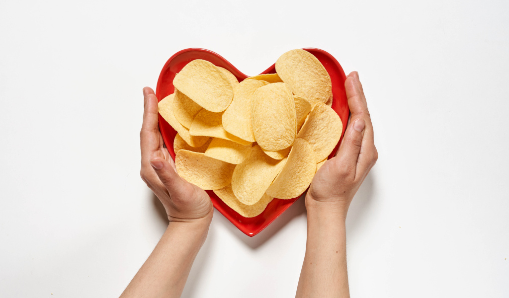 Чипсы в красной тарелке на белом фоне
