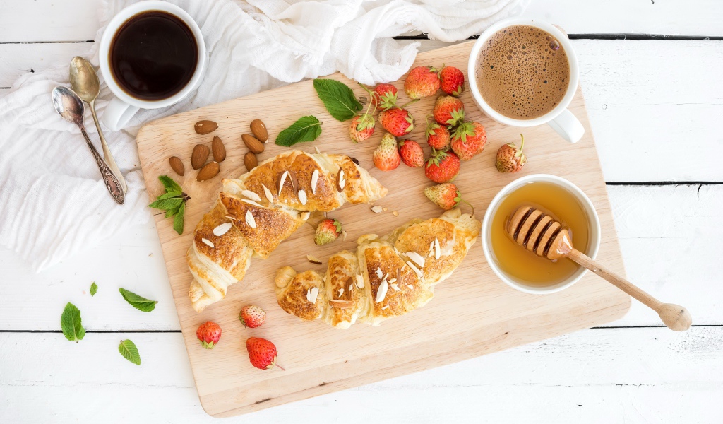 Круассаны на столе с орехами, клубникой и кофе