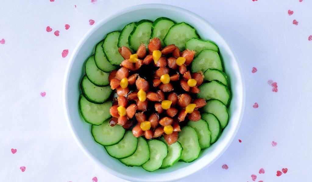 Огурцы с сосисками в тарелке на столе