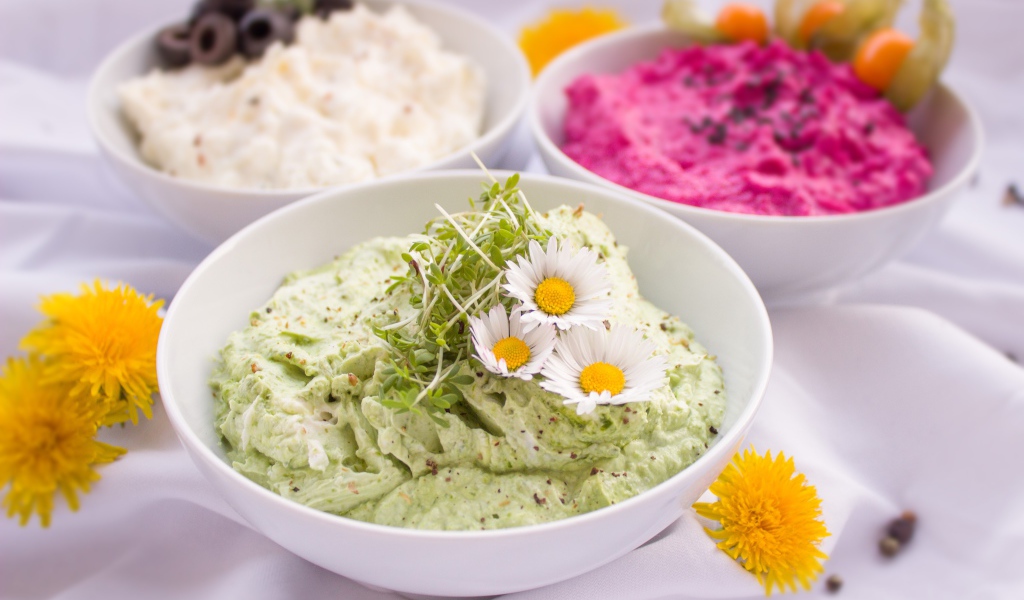 Вкусные салаты в белых мисках на столе с цветами