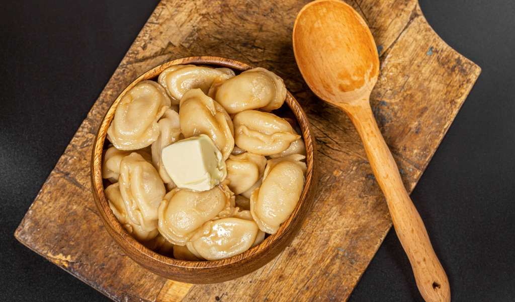 Пельмени в деревянной миске с маслом