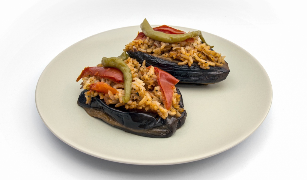Блюдо из баклажанов с рисом на большой белой тарелке