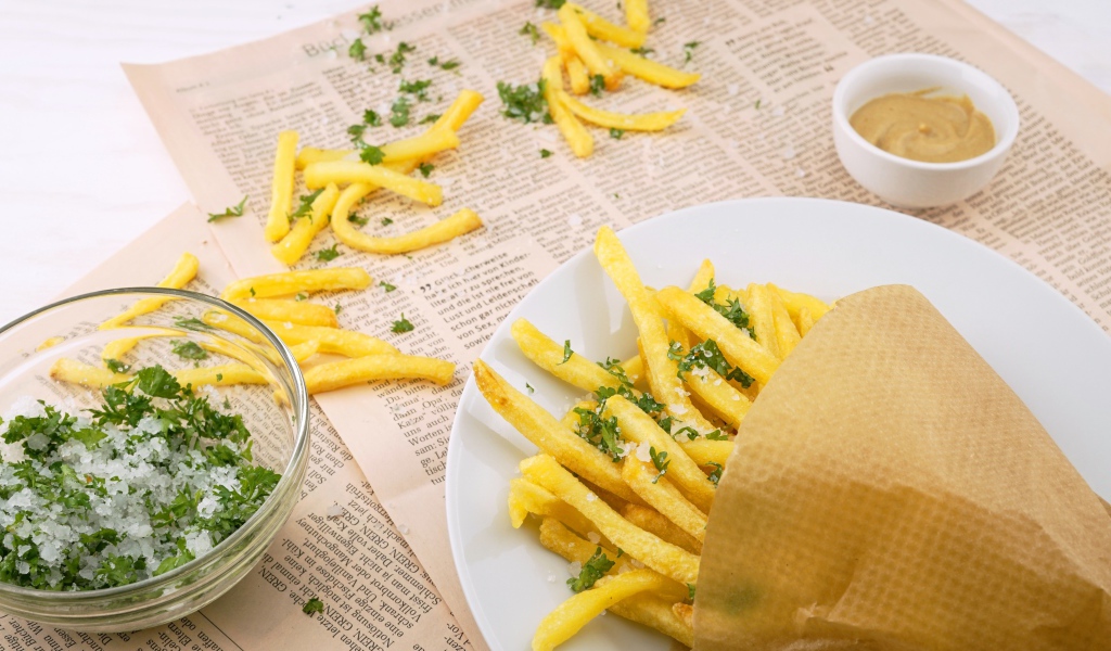 Картофель фри с зеленью на газете