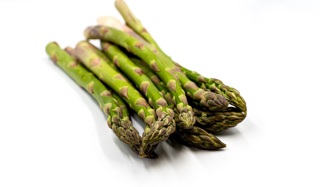 Свежая зеленая спаржа на белом столе