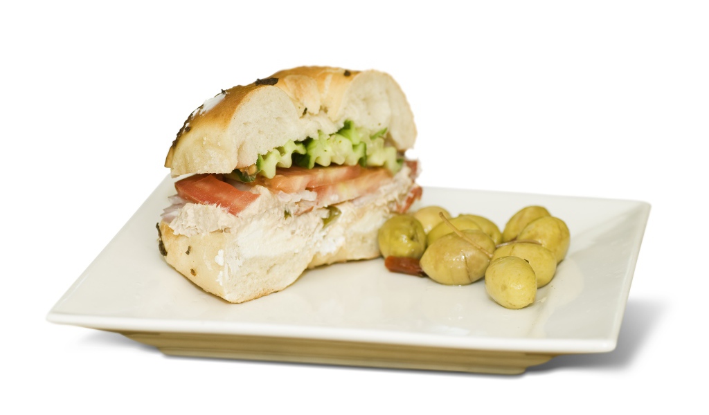 Половина гамбургера на тарелке с оливками