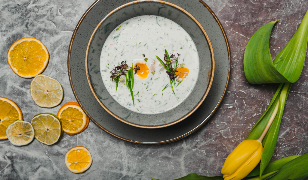 Окрошка на столе с лимонами и тюльпаном