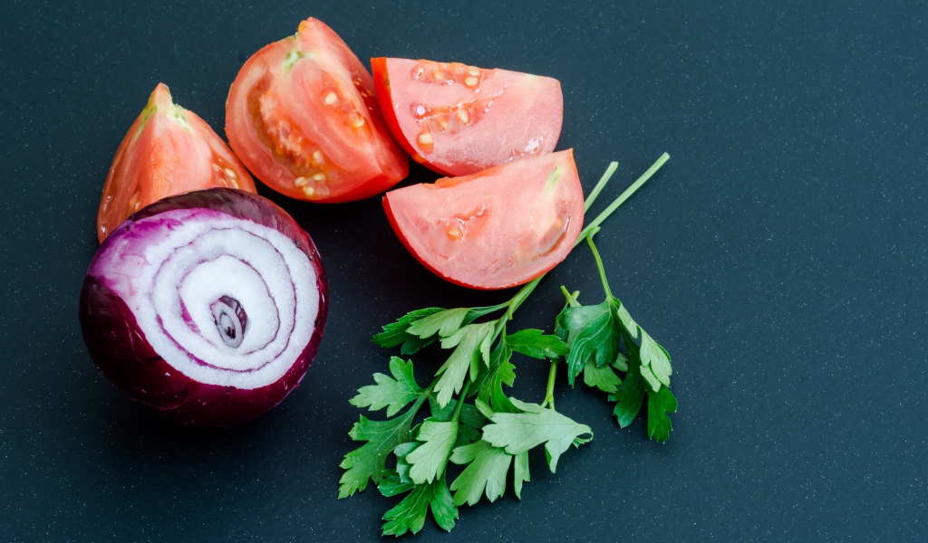 Лук, помидоры и петрушка на сером столе