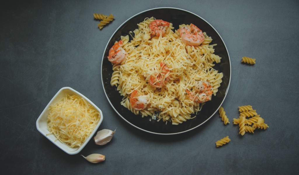 Макароны на тарелке с сыром и креветками
