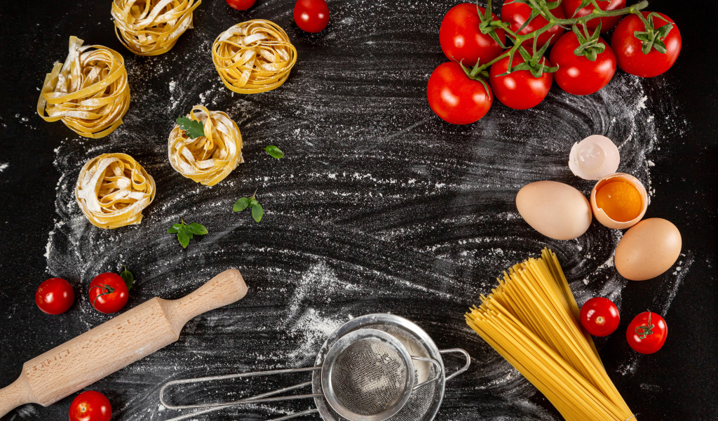 Паста с помидорами и яйцами на черном столе 