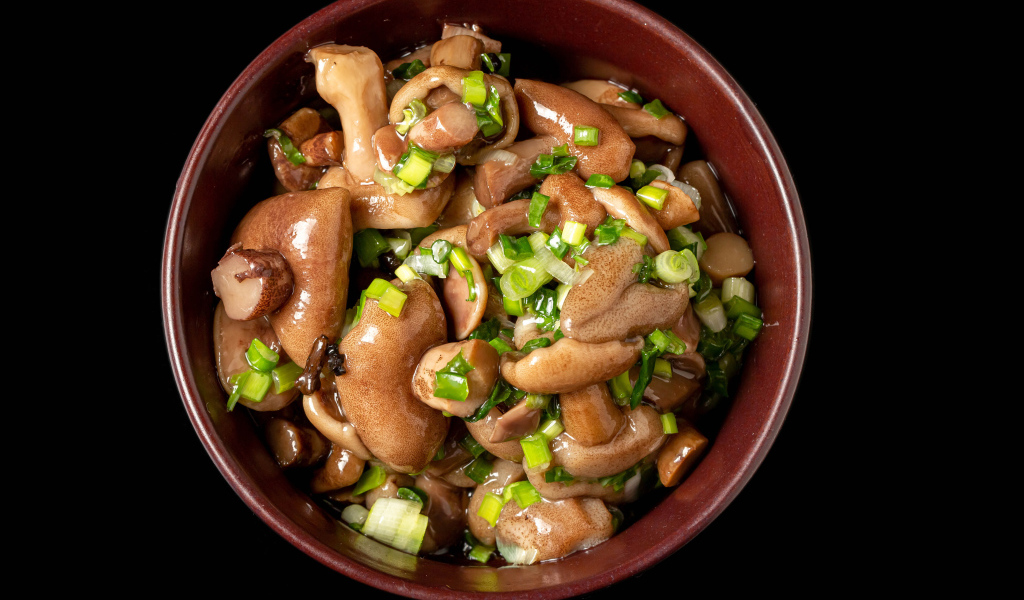 Маринованные маслята с зеленью в тарелке