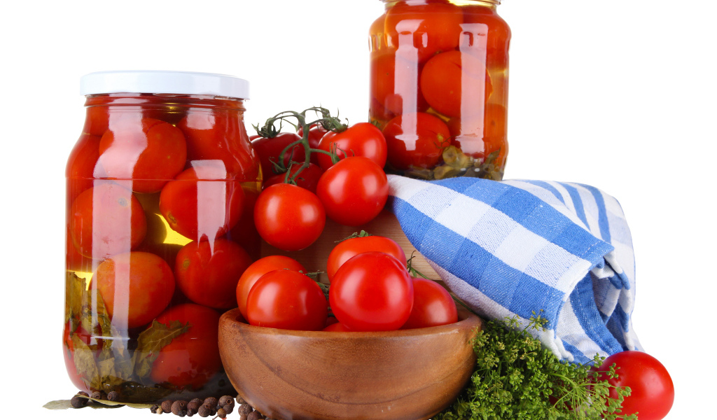 Маринованные помидоры в банках на столе со свежими