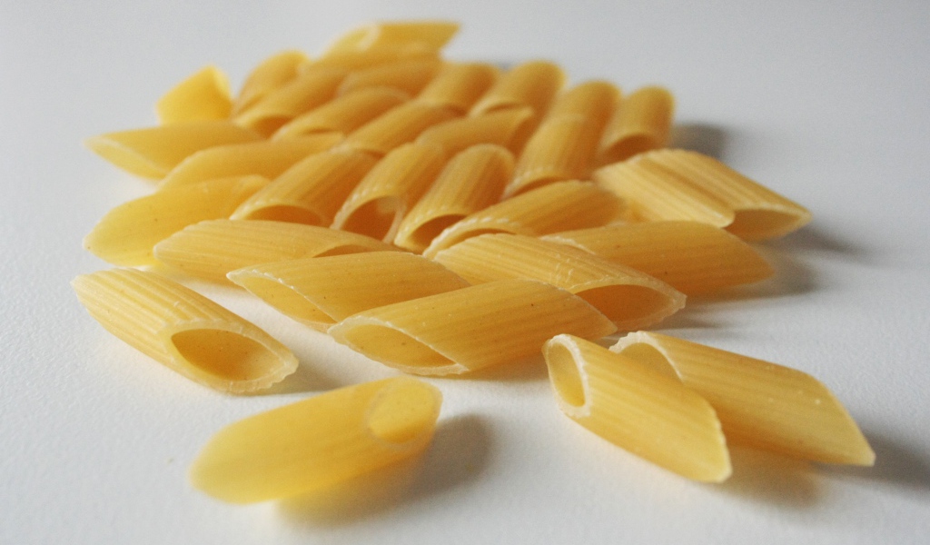 Сырые желтые макароны на сером фоне