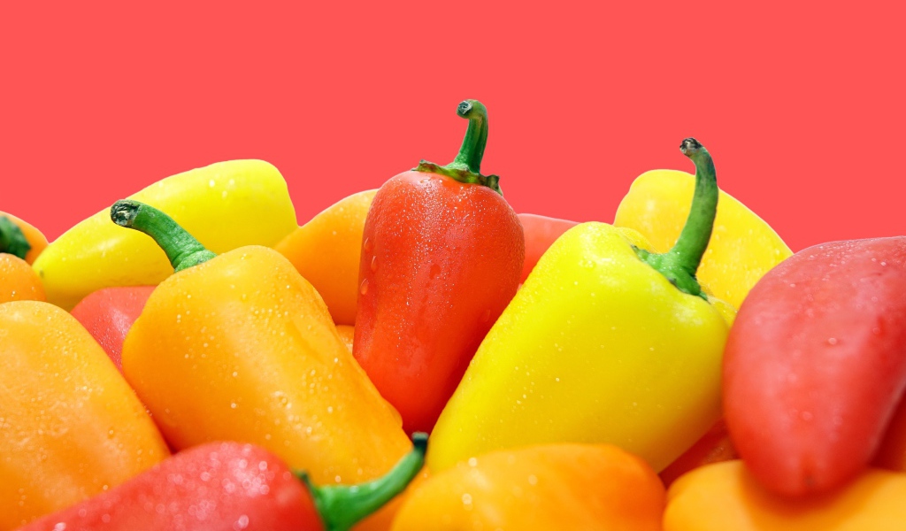 Красный и желтый перец на розовом фоне 