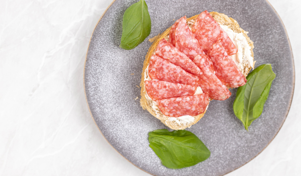 Бутерброд с маслом и колбасой на тарелке