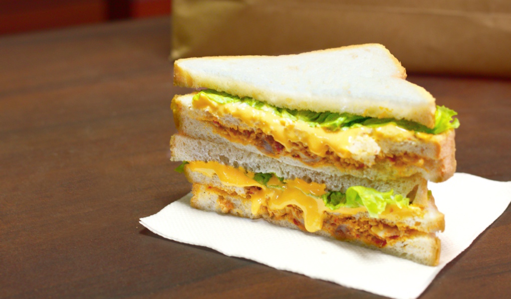 Сэндвич с сыром и листьями салата на столе