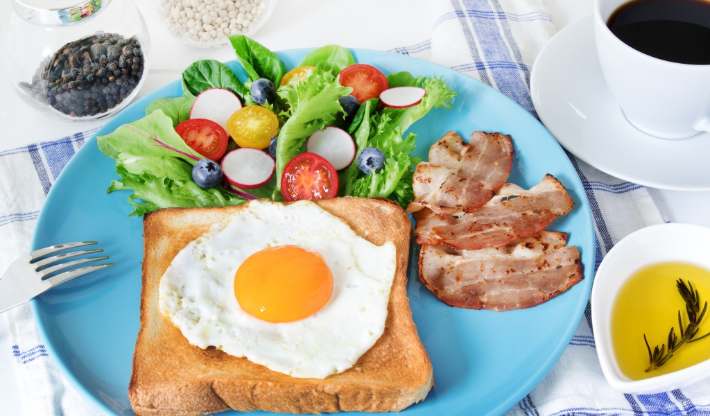 Яичница с хлебом на тарелке с салатом и беконом 