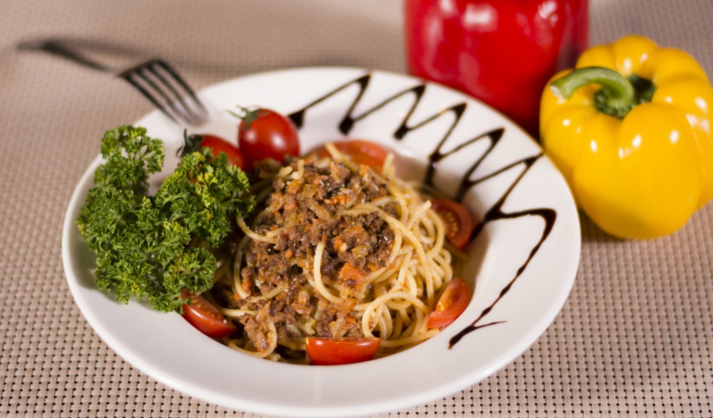 Спагетти с фаршем и помидорами в тарелке 