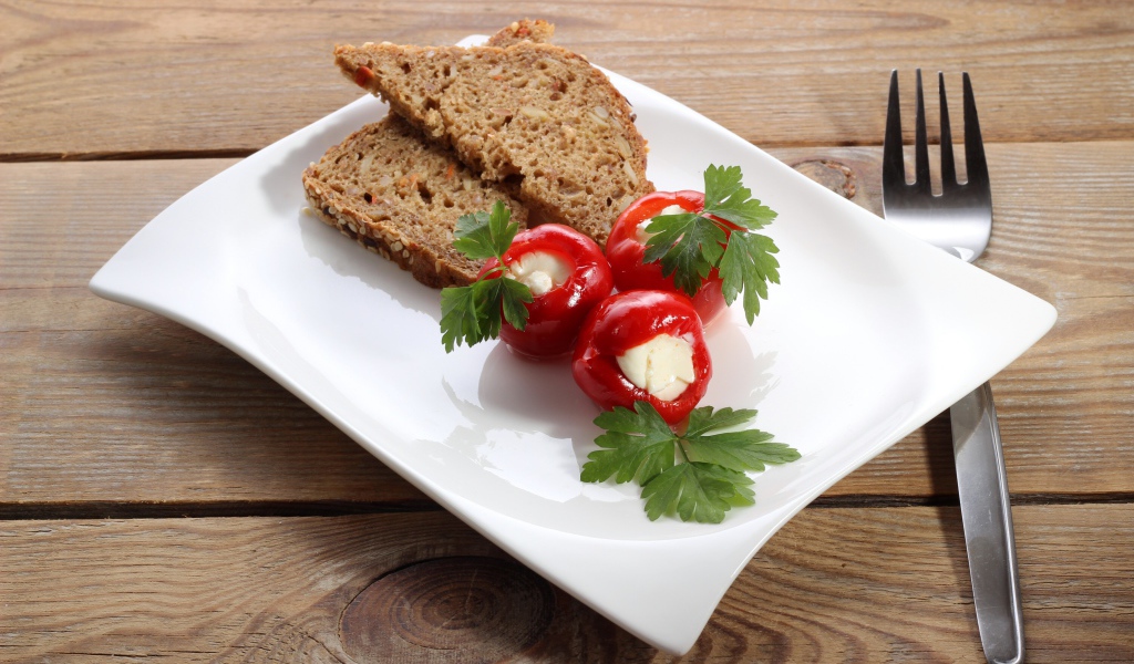 Фаршированный перец на большой белой тарелке с хлебом