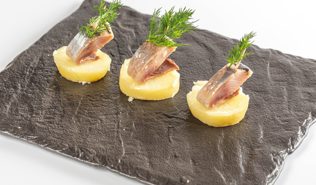 Три куска вареного картофеля с сельдью и укропом