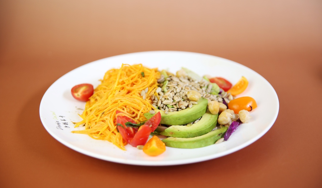 Овощи в белой тарелке на оранжевом фоне 