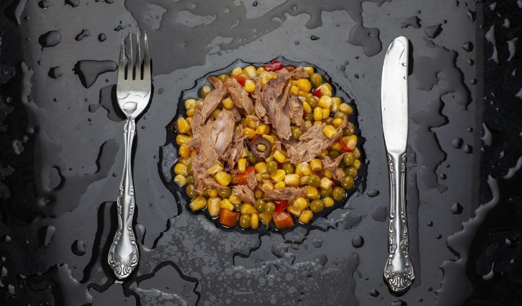 Овощи с мясом и столовыми приборами на черной поверхности