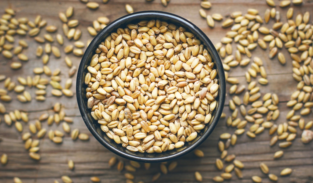 Зерна пшеницы в черной кружке на столе 