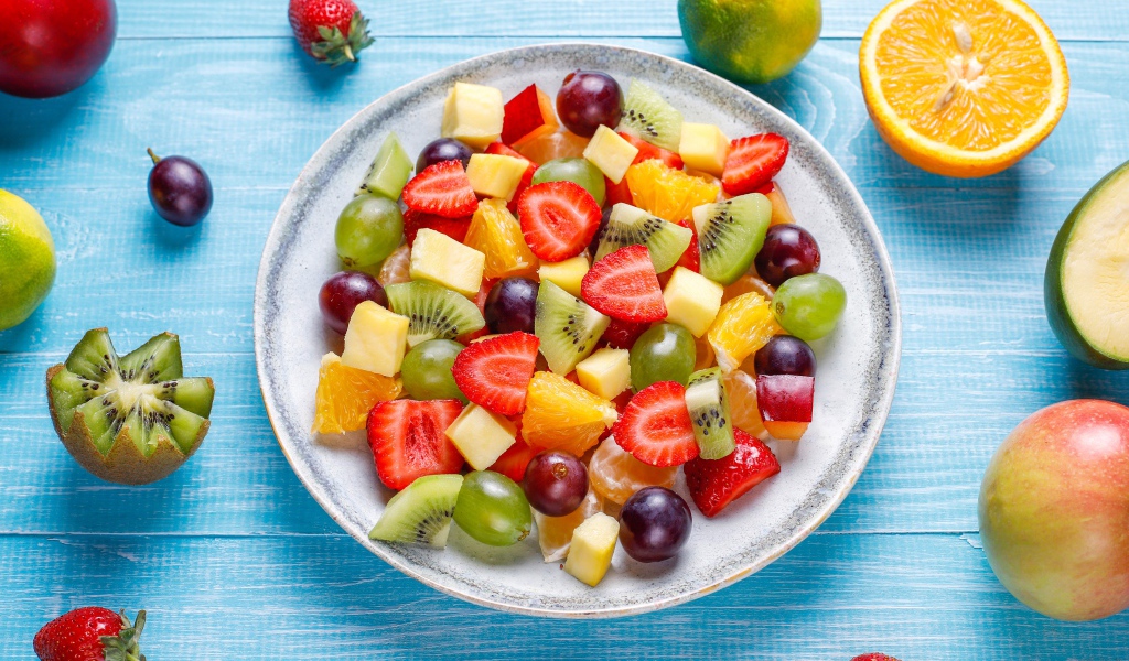 Вкусный салат из свежих овощей и ягод на голубом столе