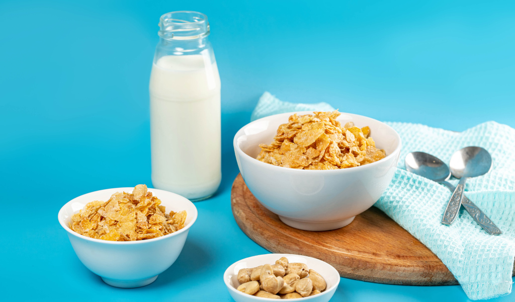 Хлопья на столе с орехами и молоком на голубом фоне
