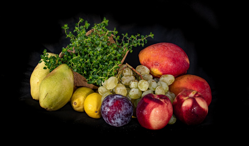 Свежие фрукты с зеленью на черном фоне 