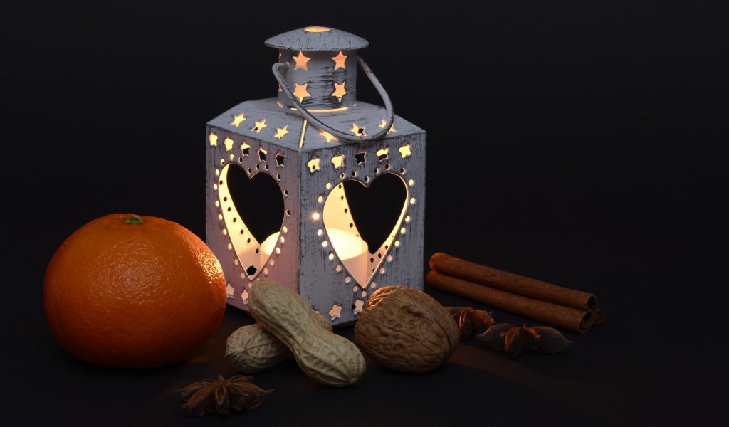 Мандарин, орехи, специи и фонарь на черном фоне