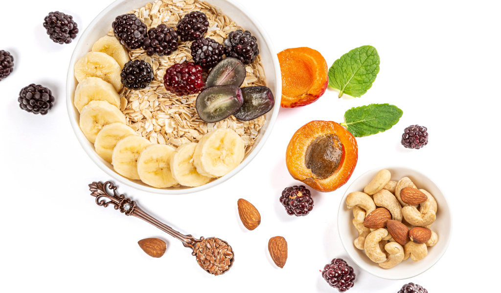 Овсяные хлопья с ягодами и орехами на белом фоне