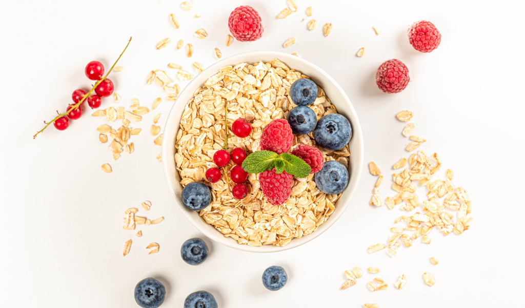 Овсяные хлопья с ягодами черники и малины на белом фоне 