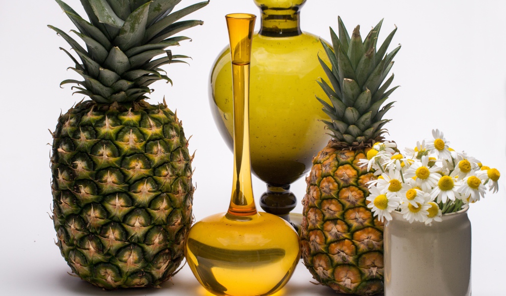 Ананасы на столе с маслом и ромашками