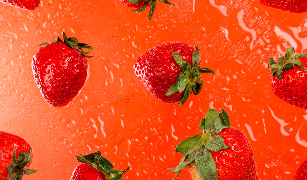 Красная клубника в воде на оранжевом фоне 