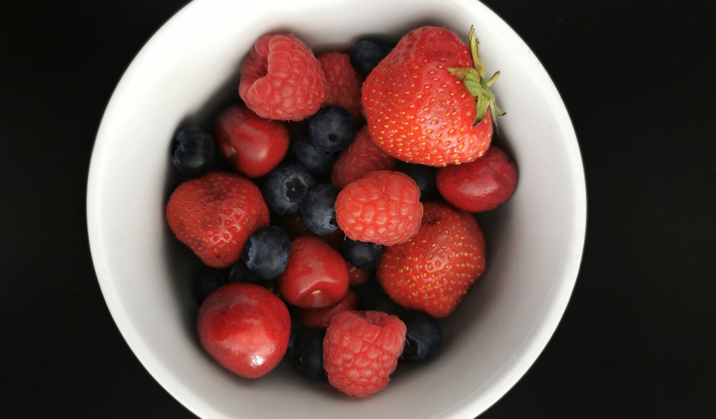 Спелые свежие ягоды в белой тарелке на белом фоне