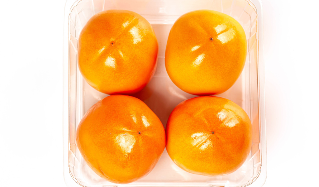 Спелая хурма с лотке на белом фоне