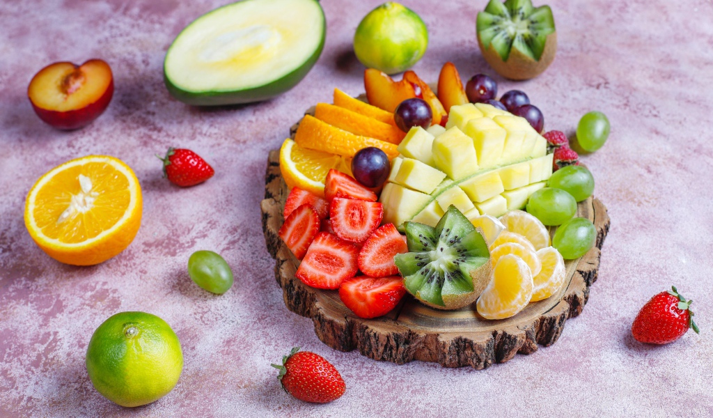 Нарезанные фрукты и ягоды на деревянной доске 