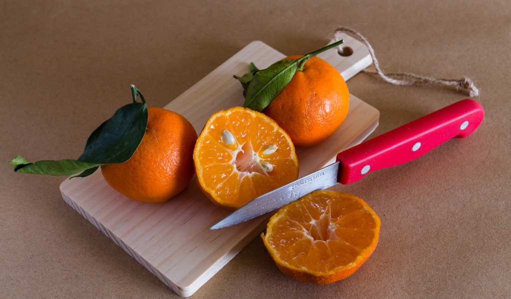Мандарины лежат на доске с ножом 