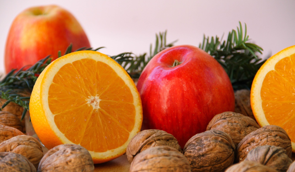 Грецкие орехи с апельсинами и яблоками на сером фоне 