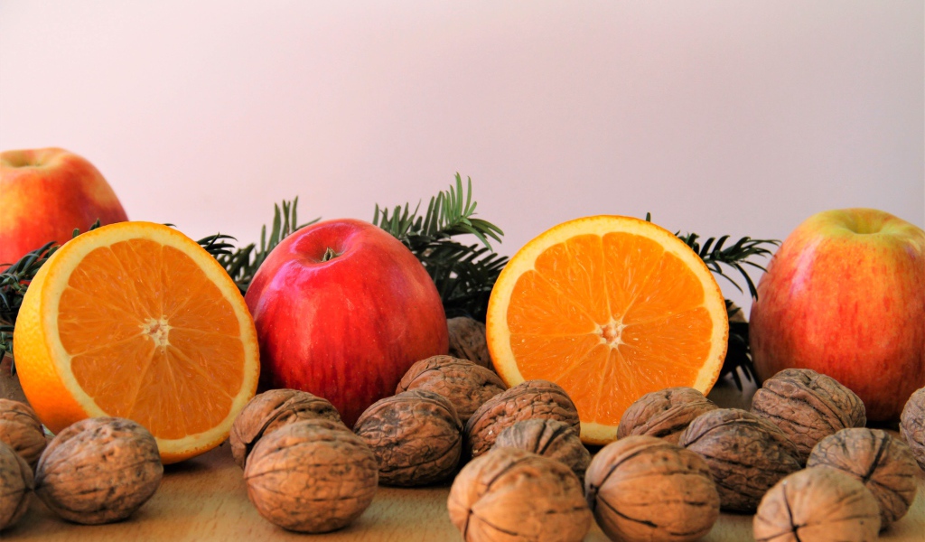 Грецкие орехи с апельсинами и яблоками на столе