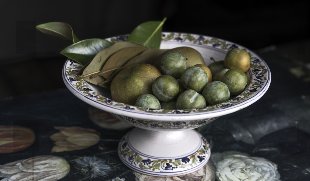 Белые сливы и зеленые яблоки в вазе на столе 