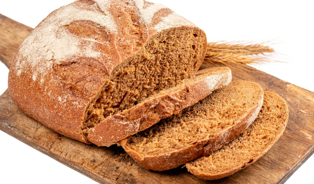 Свежий нарезанный хлеб на доске на белом фоне 