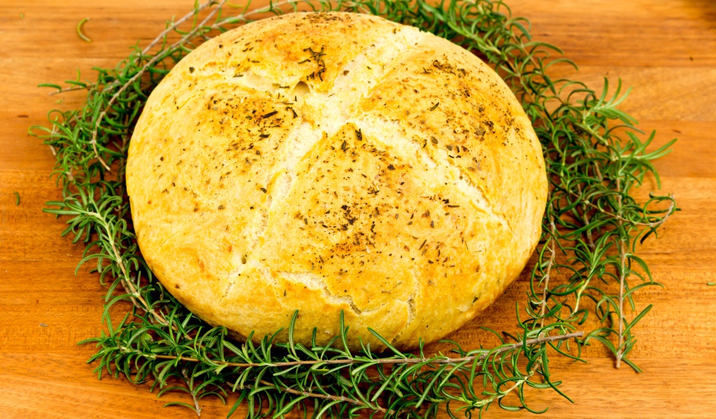 Буханка свежего ароматного хлеба с розмарином на столе