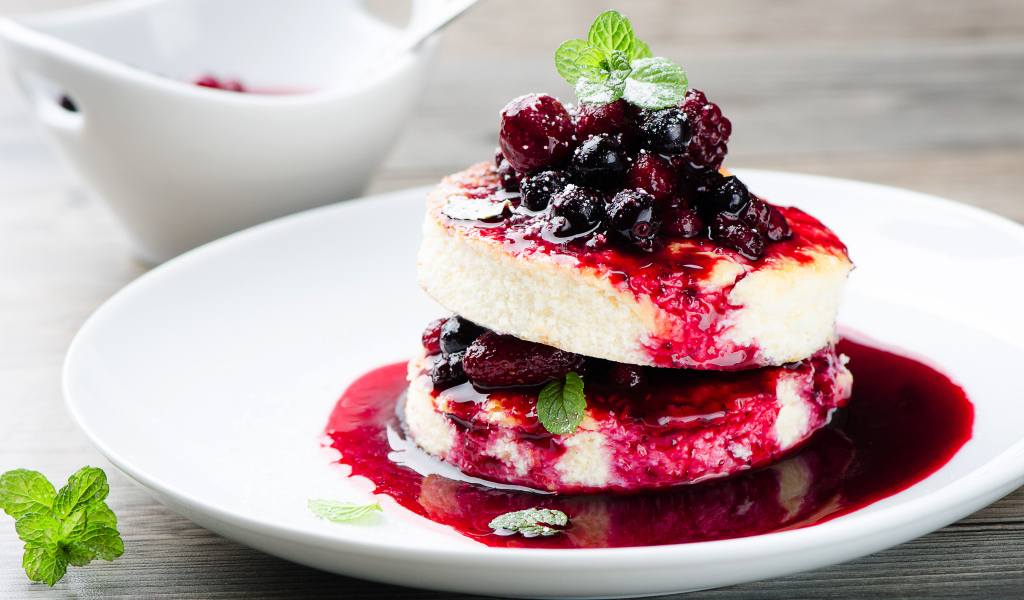 Аппетитные сырники с ягодами на белой тарелке 