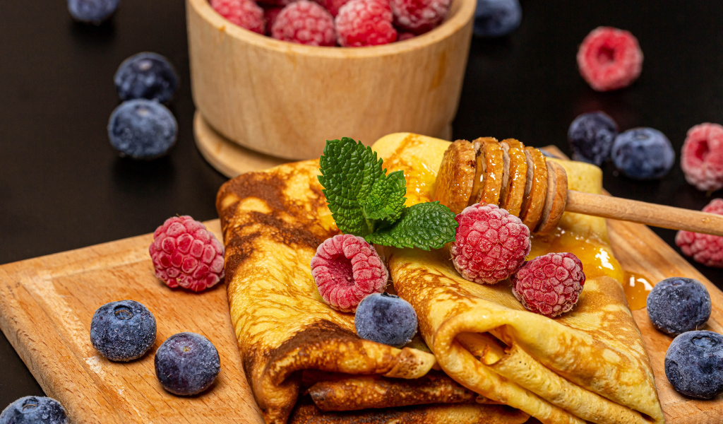 Аппетитные блины с малиной и черникой на столе