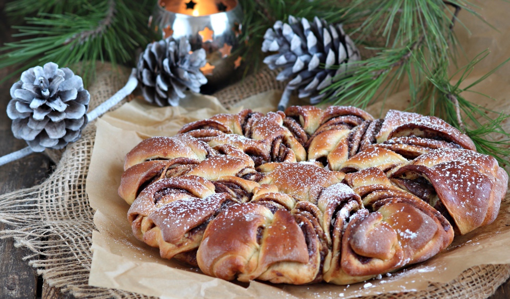 Сдобный венок с вареньем на столе с шишками