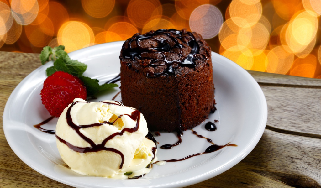 Шоколадный десерт с мороженым и клубникой на белой тарелке 