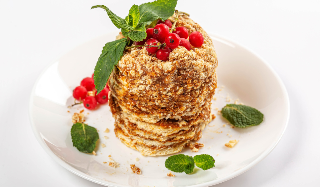 Вкусное пирожное со сгущенкой и ягодами красной смородины на белом фоне