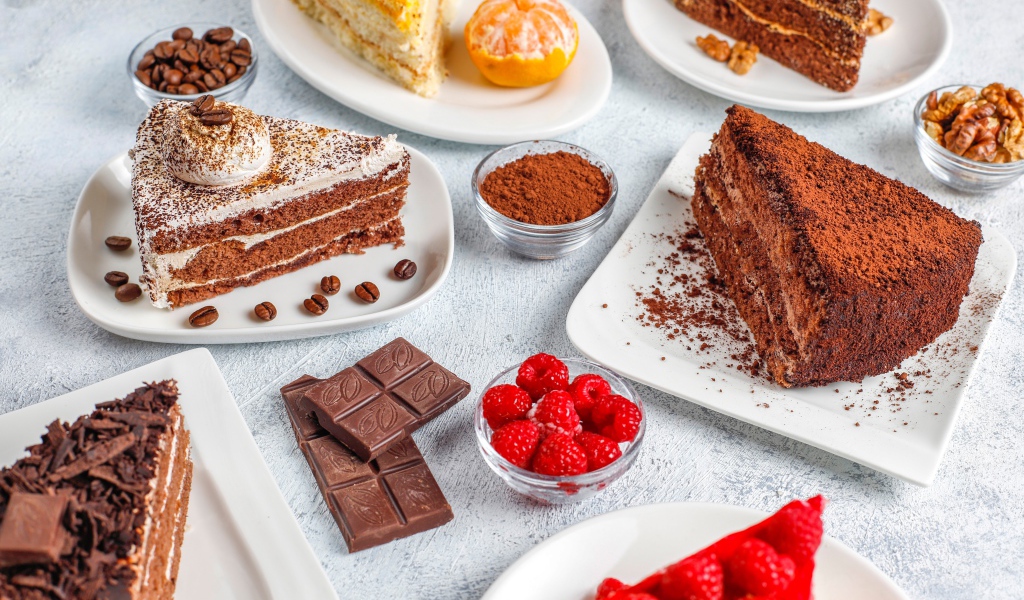 Разные куски торта на столе с малиной и шоколадом 